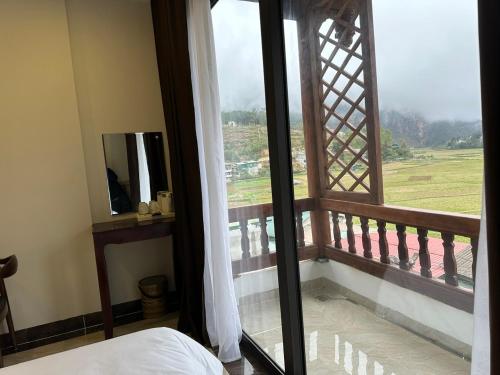 同文Dongvan Ville Du H'Mong Hotel的一间卧室设有窗户,享有田野美景