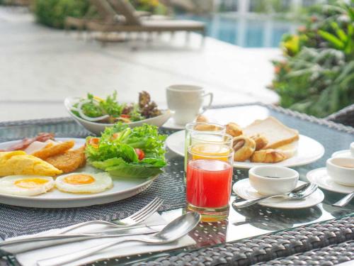芭堤雅市中心芭堤雅美居海洋度假酒店的桌上放有鸡蛋、面包和饮料