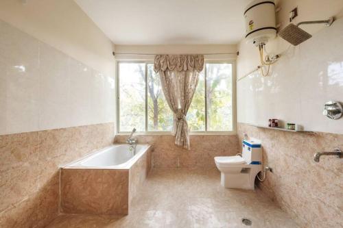 DenkanikotaVilla Exotica by JadeCaps Pvt Pool & Projector的带浴缸、卫生间和窗户的浴室