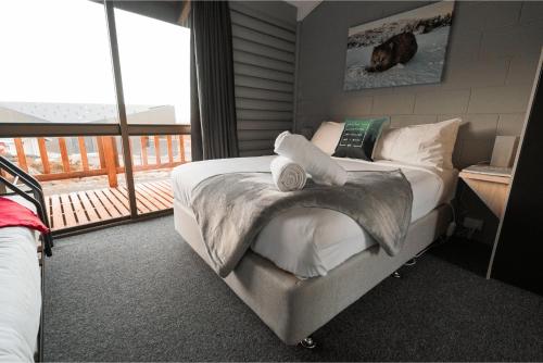 Upper BlessingtonBen Lomond Creek Cabins的一间卧室配有带白色枕头的床和阳台
