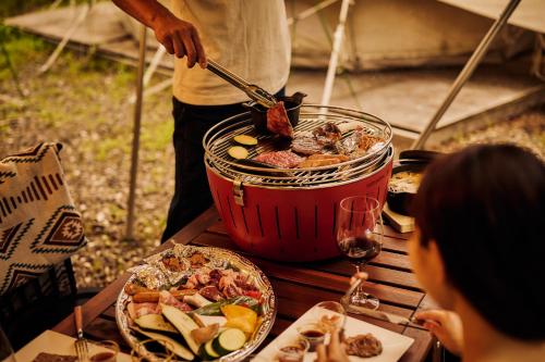 白马村Laforet Glamping Field Hakuba的餐桌上锅里做饭的人