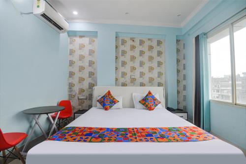 巴特那FabHotel Raj Niwas的卧室配有一张床和一张桌子及椅子