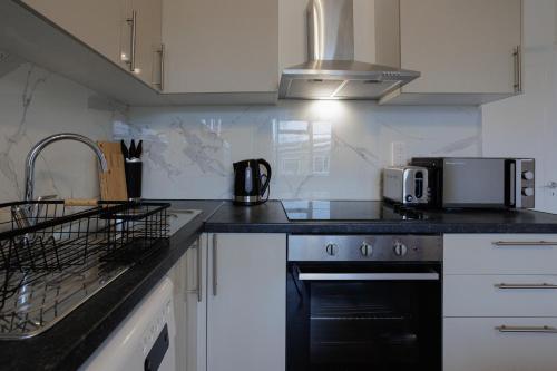 伦敦Lovely 2-bed Highbury Home的厨房配有白色橱柜和黑炉灶烤箱。