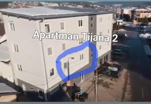 帕莱Apartman Tijana的一座白色的大建筑,上面有蓝色的箭头