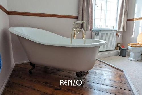 Burton JoyceBeautiful 4-bed Home in Nottingham by Renzo, Peaceful Location, Sleeps 8!的浴室铺有木地板,配有浴缸。