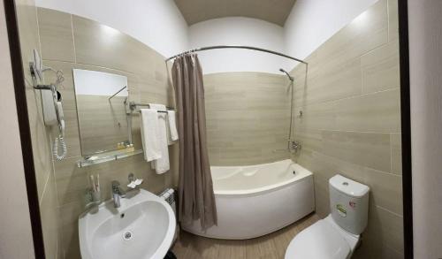 努库斯HOTEL ARAL的带浴缸、盥洗盆和卫生间的浴室