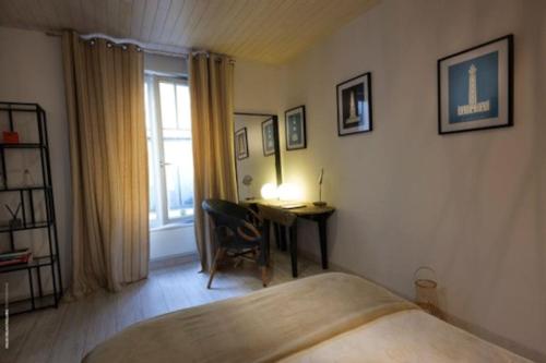 拉罗谢尔Villa Maurice avec piscine centre La Rochelle的一间卧室配有一张床、一张书桌和一个窗户。