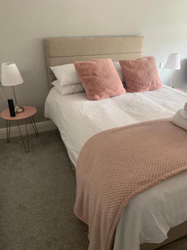 奥斯顿菲尔德Newton House的一间卧室配有一张带粉红色枕头的床和一张桌子