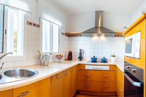 萨卡莱塔Villa Blanc的厨房配有木制橱柜、水槽和炉灶。