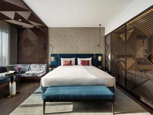 迪拜SO/ Uptown Dubai的一间卧室配有一张大床和蓝色长凳