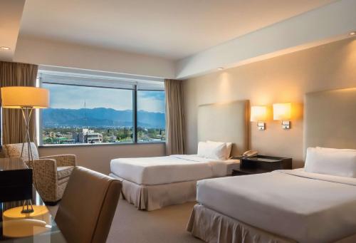 门多萨Hilton Mendoza的酒店客房设有两张床和大窗户。