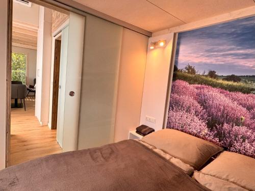 弗里茨拉尔Tiny Haus Park Fritzlar的一间卧室设有大窗户,配有紫色花卉壁画