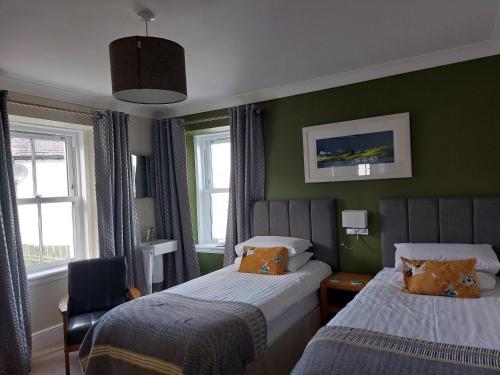 马莱格Seaview Guesthouse的配有两张床铺的绿色墙壁和窗户
