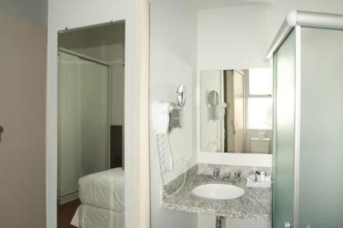 贝洛奥里藏特马科斯萨瓦西服务公寓的一间带水槽和镜子的浴室以及一张床