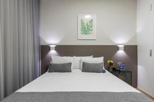 贝洛奥里藏特马科斯萨瓦西服务公寓的卧室配有一张带白色床单和枕头的大床。
