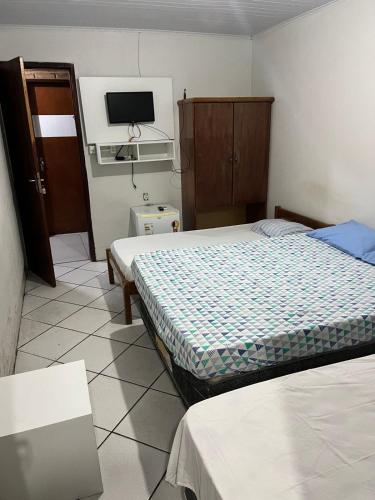 马塞约Pousada Água Viva的一间卧室设有两张床,墙上配有电视。