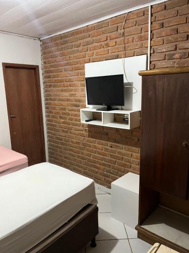 马塞约Pousada Água Viva的卧室配有1张床和1台砖墙电视