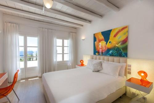 米克诺斯城Fortan 5* villa的卧室配有白色的床和墙上的绘画作品