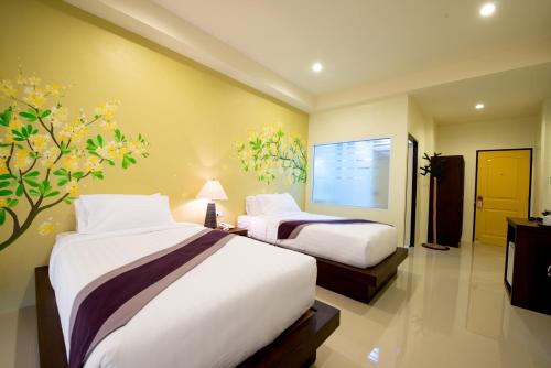 清莱玛约度假酒店 - SHA Plus的酒店客房设有两张床,墙上有一棵树。