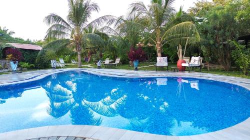 TanjiMama Africa Art Residence & Art Center Gambia的一座种植了棕榈树的蓝色游泳池
