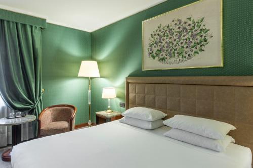 米兰Doria Grand Hotel的一间卧室设有一张床和绿色的墙壁