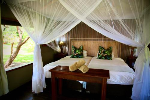 利文斯顿Zambezi Dusk的一间卧室配有两张床、窗帘和桌子