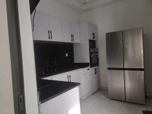 洛美Dapi Home Residence的厨房配有白色橱柜和不锈钢冰箱