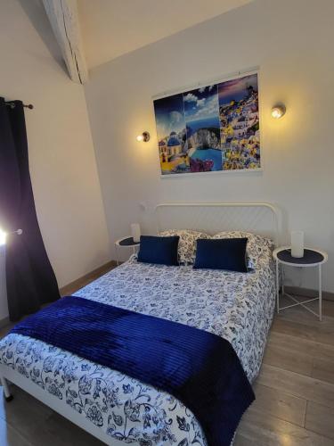 艾格-莫尔特Le Repaire du Soleil的一间卧室配有一张带蓝色棉被的床和两张桌子