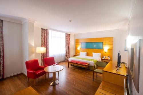拉各斯Eko Hotel Suites的酒店客房,配有床铺和红色椅子