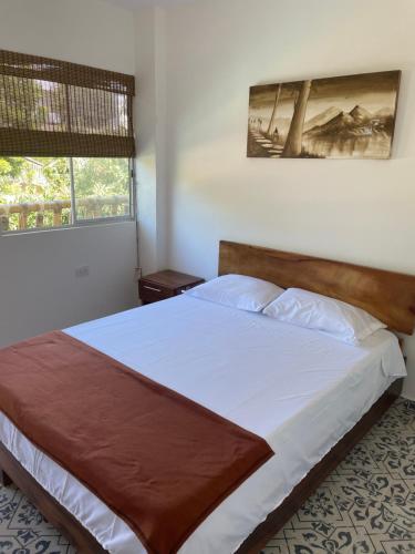 圣玛尔塔Hostal Los Arhuacos的一间卧室配有一张带白色床单的大床