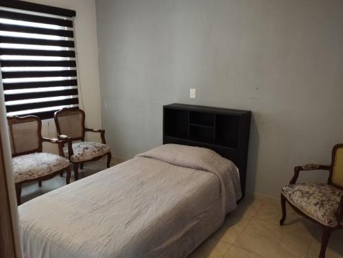 TeziutlánFabuloso Departamento en Teziutlán, Puebla的一间卧室配有一张床、两把椅子和一个窗户