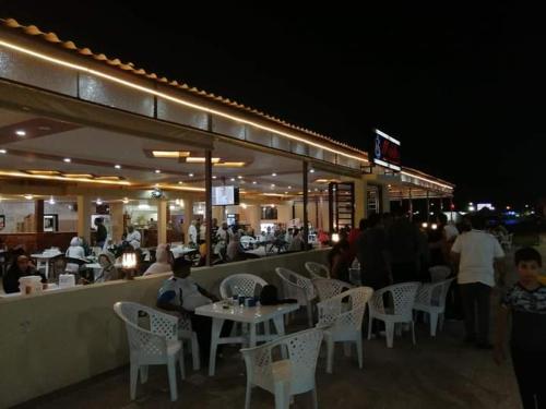 伊斯梅利亚قرية النورس مكتب السعد的一家餐厅,晚上有人坐在桌子旁