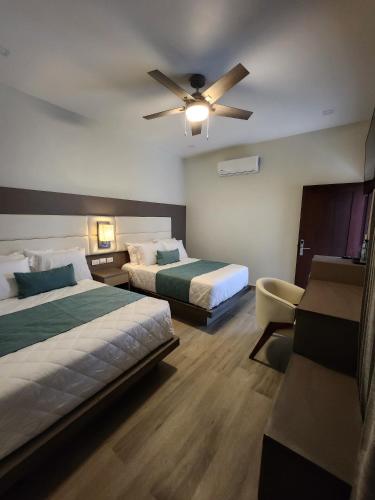 Santa ElenaHotel Tepeu的酒店客房配有两张床和吊扇。