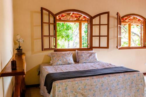 帕尔梅拉斯Kefi Chalés - Vale do Capão的一间卧室设有一张床和两个窗户。