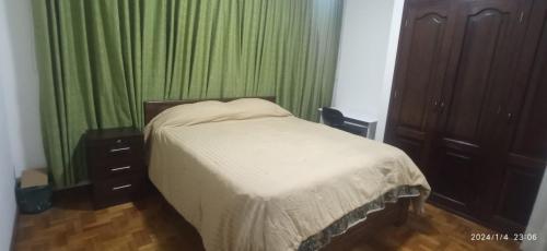 拉巴斯Para pareja o familia de 3 integrantes的一间卧室配有一张带绿帘的床