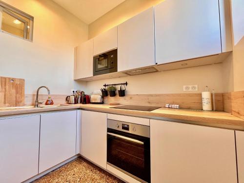 艾克斯莱班Appartement bourgeois avec terrasse et vue lac的厨房配有白色橱柜和炉灶烤箱。