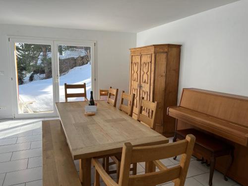 库尔瓦尔登Wohnung am Heimberg的一间带木桌和钢琴的用餐室