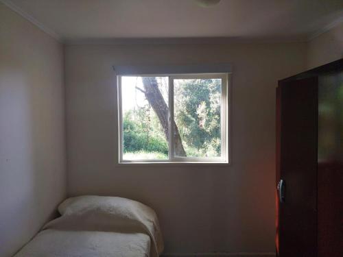 奥索尔诺Cabaña Campestre的一间小卧室,角落里设有一个窗户