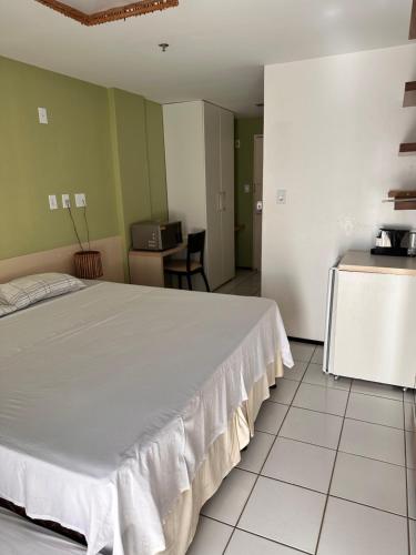 巴雷里尼亚斯Gran Lençóis Flat Residence的一间带白色大床的卧室和一间厨房