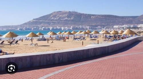 阿加迪尔Appartements à AGADIR 10min de la plage的海滩上放着一把遮阳伞,大海