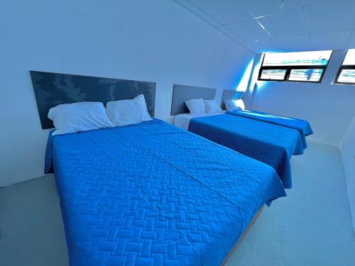 危地马拉Hotel Citadin zona 5的蓝色灯光客房内的两张床