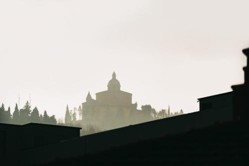 博洛尼亚A Casa dello Steno - Unicità Rustica的雾中山丘上建筑物的轮廓