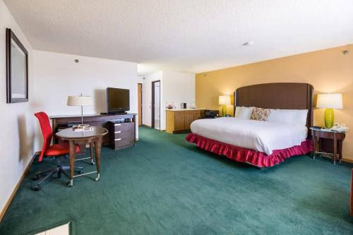 莱恩斯Alliance Hotel and Suites的酒店客房配有一张床、一张书桌和一台电视。