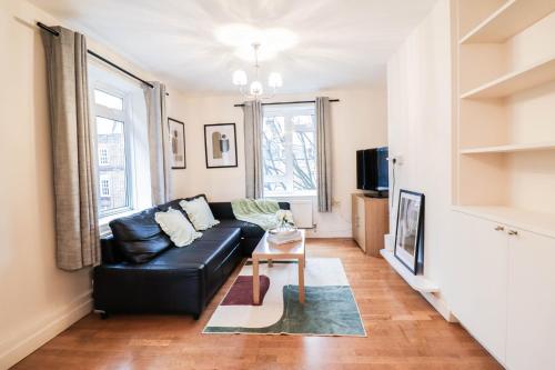伦敦Fantastic 2 Bed London Apartment的客厅配有黑色真皮沙发和桌子
