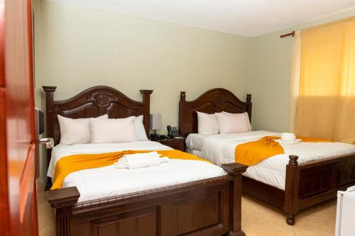 太子港Vivy Hill's Hotel的一间卧室配有两张带橙色和白色床单的床