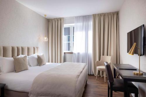 圣雅克德拉朗德Best Western Plus Hôtel Isidore的酒店客房设有一张大床和一张书桌。