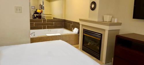 加纳诺克Riviera Inn And Suites 1000 Islands的一间卧室设有壁炉、一张床和一个浴缸。