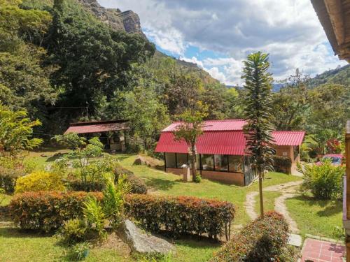 MachetáHotel Campestre Rocas Del Paraíso的花园中一座红色屋顶的房子