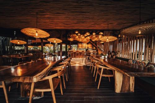 乌鲁瓦图Kayu Mama Resort and Spa的餐厅设有木桌、椅子和吊灯。