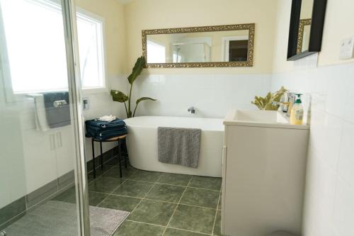 Upwey帕迪溪休闲度假屋的带浴缸、水槽和镜子的浴室